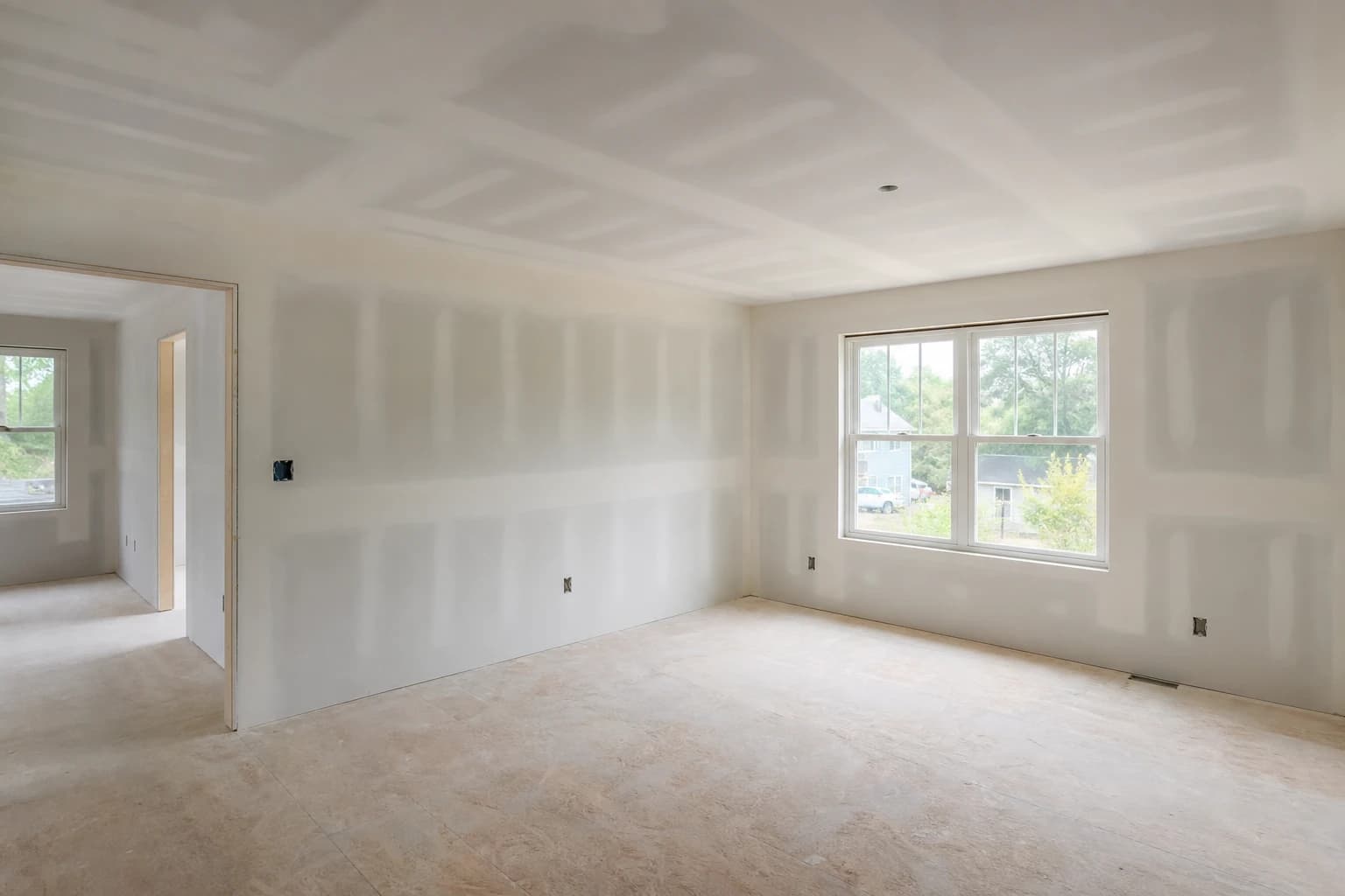 Newly installed drywall in a room addition with sanded, finished walls and ceiling ready for primer