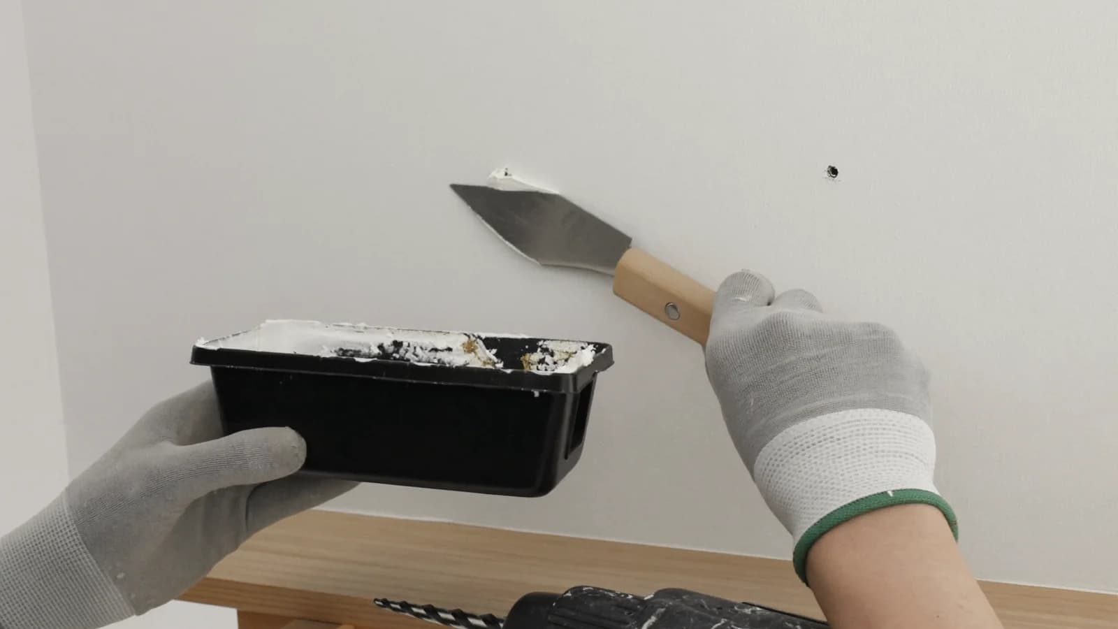 Joint compound being applied over re-secured fasteners on a drywall wall