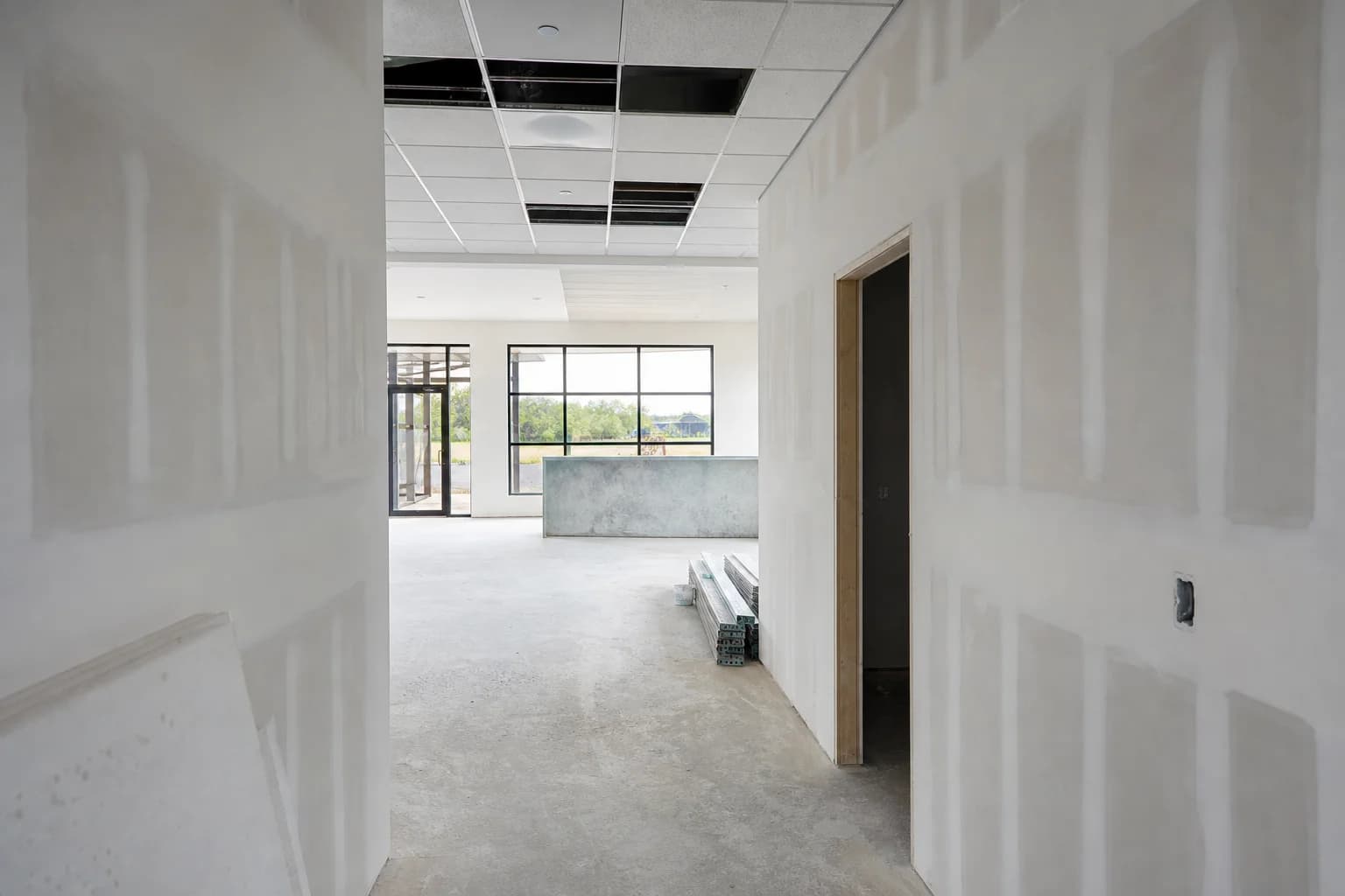 A finished drywall corridor and reception area mid tenant improvement build-out with ceiling tiles partially installed, a common commercial drywall project type in Chester County, PA